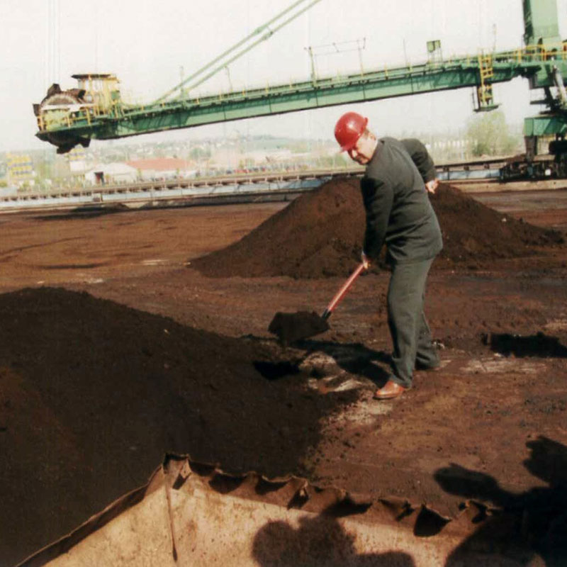 Ein Mitarbeiter mit Helm, der Kohle schaufelt