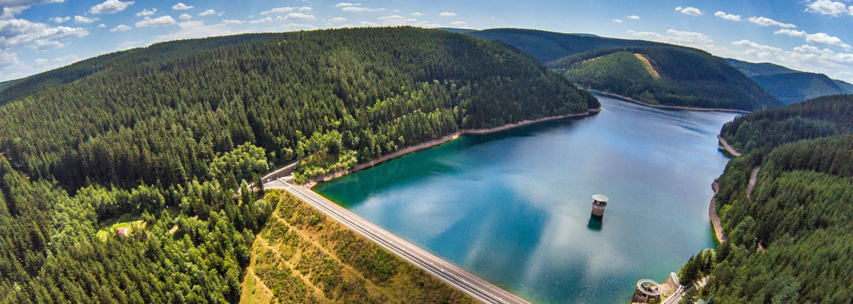 Talsperre im Wald mit Staumauer und blauem Wasser