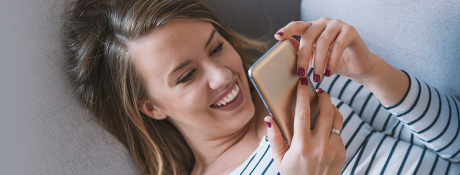 Frau mit Smartphone auf dem Sofa